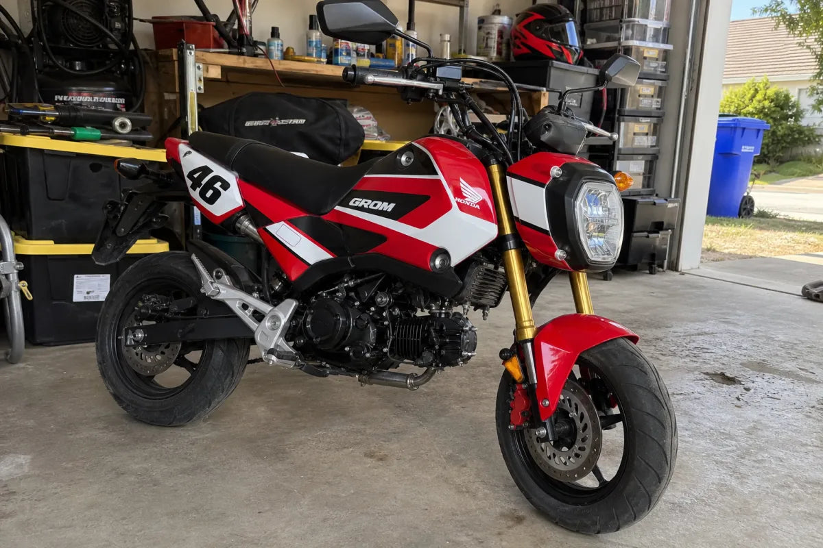 Honda Grom with red OEM-style race graphics in a home garage